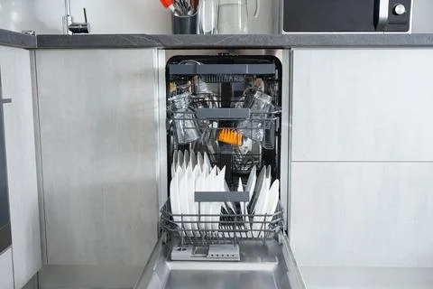 Dishwasher machine, open and loaded with dishes in the kitchen, after washing Stock Photos