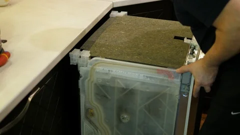 Dishwasher machine pushed back in to place after being fixed by a worker 库存影片 123605714