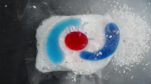 Dishwasher Tablet Begins to Dissolve, Colors Spreading and Detergent Granules Stock Footage 283307747