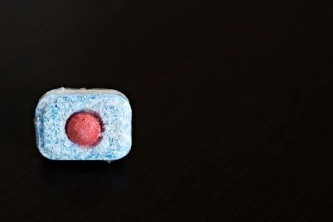 A dishwasher tablet on a dark background. Close-up Stock Photos