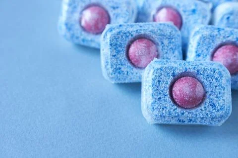 Dishwasher tablets on a blue background. Copy space. Stock Photos
