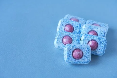 Dishwasher tablets on blue background. Stock Photos