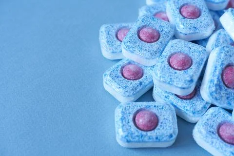 Dishwasher tablets on blue background, selective focus. Copy space. Stock Photos