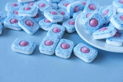 Dishwasher tablets on a blue background. Use of dishwashing powder. Stock Photos