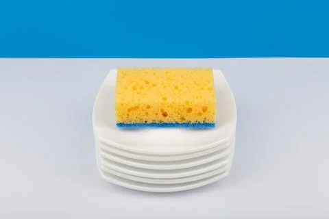 Dishwashing concept, high angle view of cleaning sponge on pile of clean saucers Stock Photos