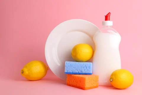 Dishwashing detergent and lemons on a colored background Stock Photos