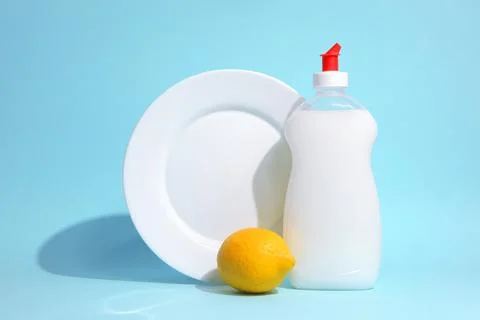 Dishwashing detergent and lemons on a colored background Stock Photos