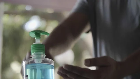 Disinfecting hands using hand sanitiser from the bottle and rubs it on the hands Stock Footage 130257374
