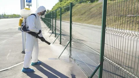 Disinfector in protective suit processes territory of streets, sprays poison Stock Footage 137758661