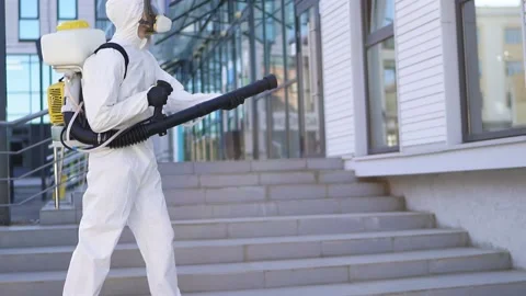 Disinfector in protective suit processes territory of streets, sprays poison Stock Footage 140460024