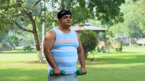 A disinterested Indian man doing a workout with dumbbells - uncomfortable fit... Stock-Footage 264016044