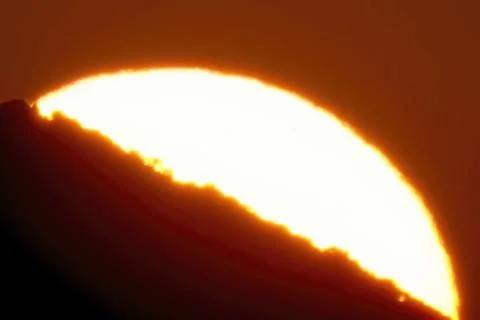 The disk of sun going into the sunset behind the obstacle Stock Photos