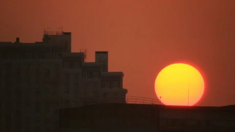 Disk of sunset sun hides behind building Stock Footage 148470773