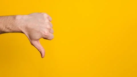 Dislike sign. man hand with thumb down over yellow background with copy space Stock Photos