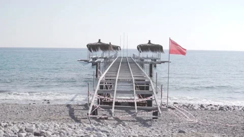 A dismantled pier with a red flag goes into the sea Stock Footage 233488254