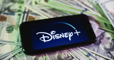 Disney+ Logo on iphone surrounded by $100 Bills. Disney Profits Layout. Stock Footage 169007841