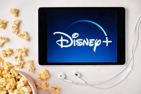 Disney plus logo on the screen of the tablet laying on the white table and Stock Photos