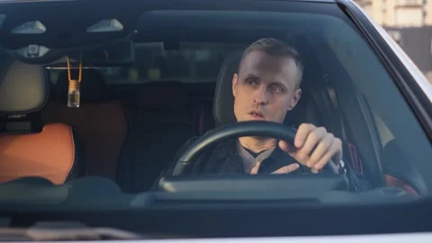 Disoriented driver having heart attack in car Stock Footage 321311890