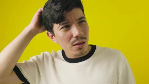 Disoriented freckled young man looking for a direction on a yellow background Stock Footage 311878440