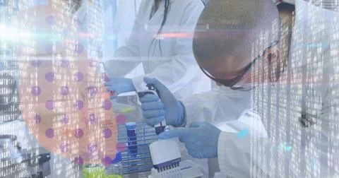 Dispensing scientist in lab coat using electronic pipette into multiwell plate Stockfoto's
