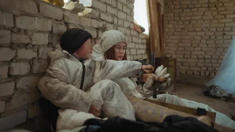 Displaced Children Interact in Makeshift Brick Shelter Holding Rusted Tool 動画素材 347085989