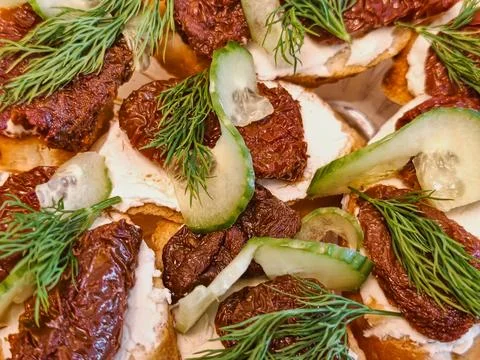 A display of bread with cream cheese, sun-dried tomatoes, cucumber slices, an Stock Photos