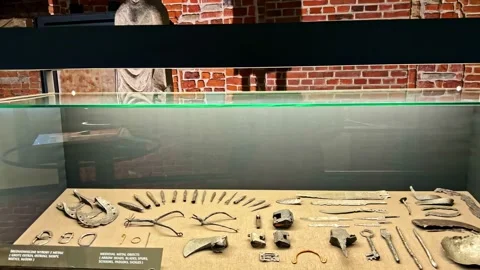Display case of medieval metal objects in brick room, Wawel Royal Castle Museum Stock Footage 328987265