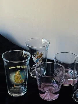 Display of decorative glasses featuring unique designs and colors on a blac.. Foto stock