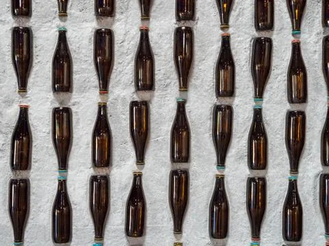 A display of mounted empty beer bottles embedded into a stone wall Foto stock