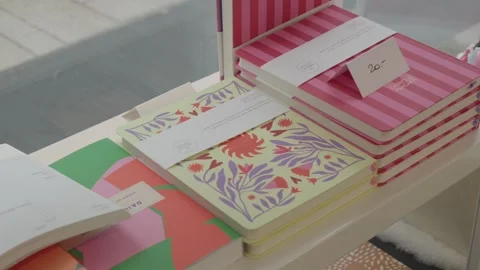 Display of notebooks for sale inside a paper shop, flower motif design Stock Footage 320943497