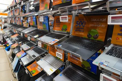 Display of various laptops in an electronics store with promotional signs and Stock Photos