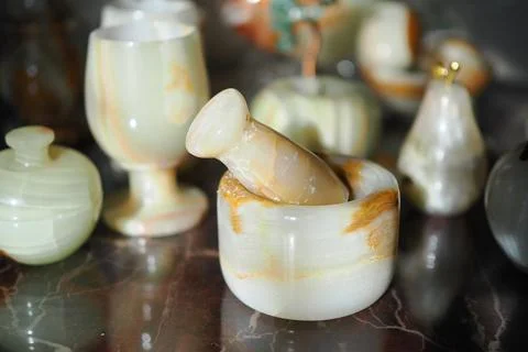 Display of various stone containers and a mortar on a marble surface Stock Photos