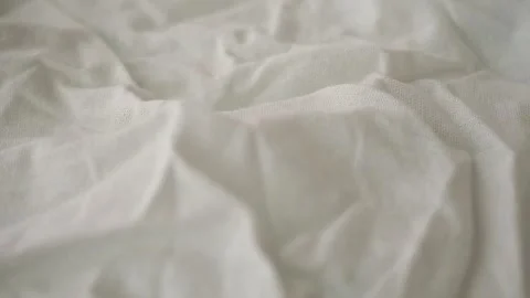 Displaying a close view of wrinkled white fabric on a soft surface Stock Footage 347572432