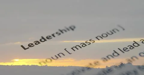 Displaying closeup dictionary entry tilting over sunset sky, showing word Stock Illustration