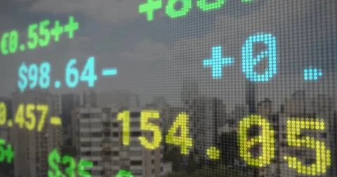 Displaying dot-matrix stock ticker updating price readouts over hazy city Fotos de archivo
