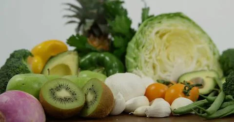 Displaying green cabbage half, pineapple crown and avocado half among produce on Stock Photos
