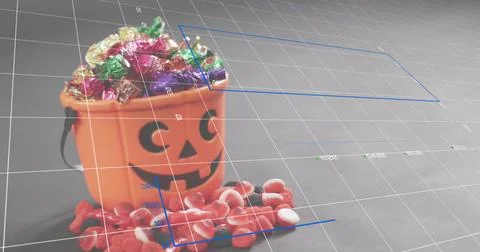 Displaying orange jack-o'-lantern bucket holding foil candies on gray tabletop Photos
