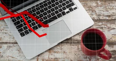 Displaying silver laptop keyboard angled on worn desk, projecting red down arrow Stock Photos