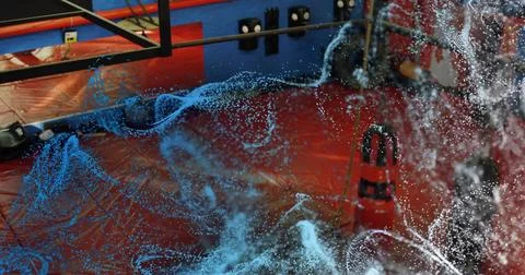 Displaying swirling fluid simulation across red padded mat in demo lab, with Stock Photos