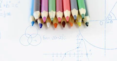 Displaying ten colored pencils lining up on white paper at study desk with bl Fotos de archivo