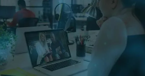 Displaying two colleagues conducting remote meeting on laptop at office desk Stock Photos