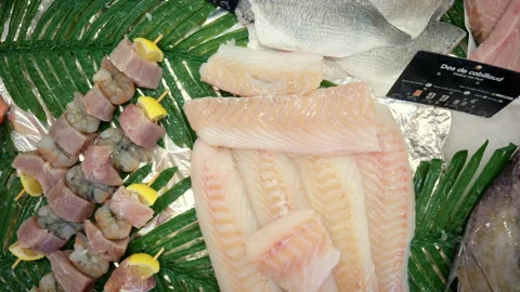 Displaying various raw seafood products including cod fillets and whole fish, Stock Footage 343160639