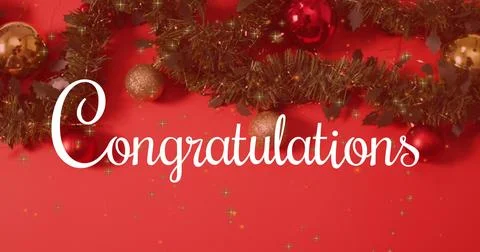 Displaying white cursive 'Congratulations' text on red wall, with green tinsel Stock Photos