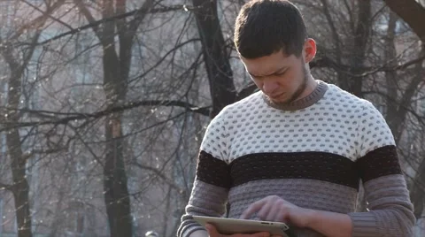 Displeased man using tablet outside in park Stock Footage 61865311
