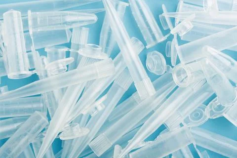 Disposable clear lab plastic tubes and pipette tips form blue banner backgrou Stock Photos