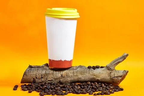 Disposable coffee cup with a vibrant design spills dark coffee and yellow lid ho Stock Photos