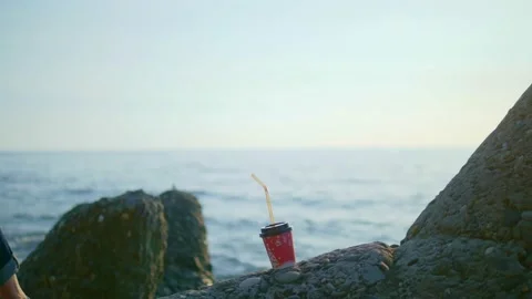 Disposable cup on a boulder against the background of the sea Stock Footage 146900424