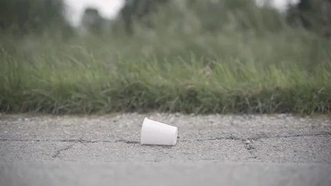 A disposable cup is lying on the floor. Then the hand lifts it up Stock Footage 242090649