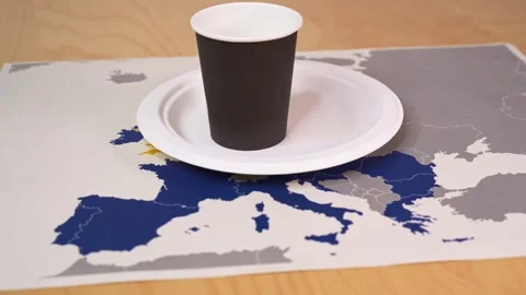 Disposable cups and plates sit on a map of europe, symbolizing the single-use pl Stock Footage 303653317