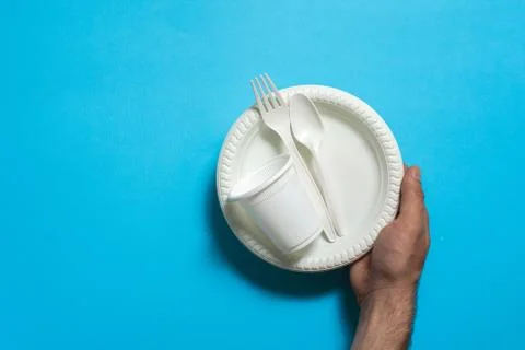 Disposable eco-friendly fork, spoon, plate and cup of corn starch in hand Stock Photos